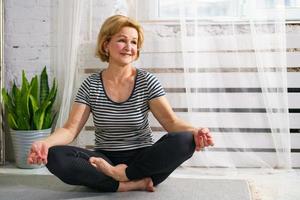 Sweetheart sport mature woman meditating at home in the room photo