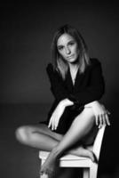 woman posing sitting on a chair in jacket and lingerie, black and white photo