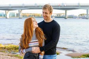 Young couple is standing on the river bank hugging photo