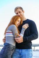 Young couple is standing on the river bank hugging photo