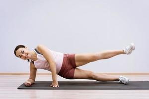 Happy woman doing yoga at home against wall background photo