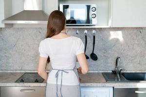 mujer joven lava una sierra eléctrica en la cocina en casa con guantes de goma. foto