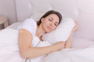 fotografía de una joven dormida yace en la cama con los ojos cerrados sobre un fondo blanco foto