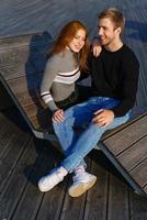 young couple are sitting in the park on a wooden bench hugging photo