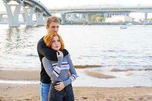 Young couple is standing on the river bank hugging photo