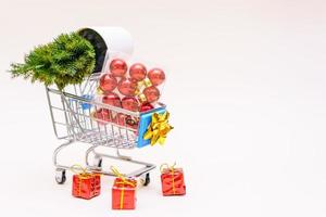 Red christmas balls and an artificial small christmas tree with gifts in photo