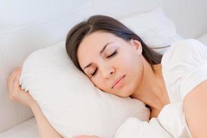 Serene calm woman sleeping in comfortable bed lying on soft pillow orthopedic photo