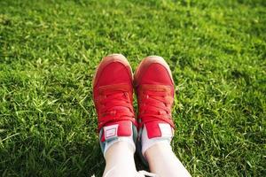 female legs in sneakers on a background of green grass photo