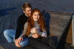 young couple are sitting in the park on a wooden bench hugging photo
