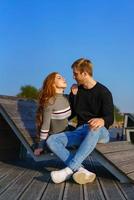 happy couple guy and girl are sitting on a wooden deck hugging photo