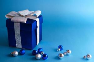 caja de regalo azul con bolas de navidad sobre fondo azul foto