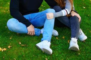 Happy young couple sit in an embrace in the park on the grass photo