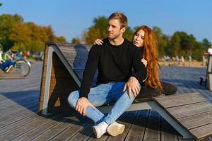happy couple guy and girl are sitting on a wooden deck hugging photo