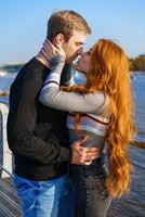 Young couple is standing on the river bank hugging photo