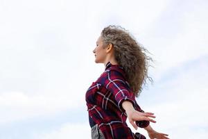 la mujer extendió sus brazos a los lados contra el cielo foto