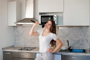 Photo young woman starting to prepare a family dinner, singing like a rock star