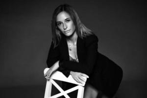 mujer posando sentada en una silla con chaqueta y lencería, foto en blanco y negro