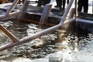 pueblos cerca del agujero de hielo en el lago congelado foto