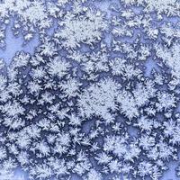 snowflakes and frost on frozen window in winter photo