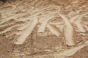 Tire track mark lines shape on dry sand background. Trail tyre imprint from heavy machinery. Vehicle shape. Road construction site backdrop concept. Trace of wheel pattern on mud. Nature texture. photo