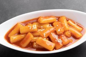 pastel de arroz coreano frito tteokbokki tteokbokki picante comida de estilo coreano en una taza blanca. foto