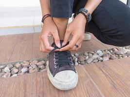 photo of female hands wearing and tying casual shoelaces