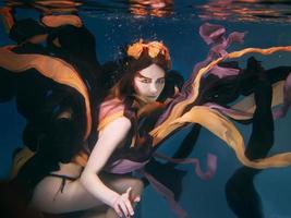 hermosa mujer joven artística en vestido bailando bajo el agua. sirena, cosecha, danza, concepto de hadas foto
