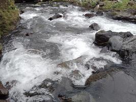 River stream flowing throw rocks to mountain lake. landscape of water, stones in the river. photo