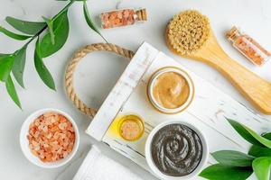 Natural cosmetics product background. zero waste, eco friendly bathroom and spa accessories. Clay mask, natural scrub, massaging brush, himalayan salt on a wooden tray photo