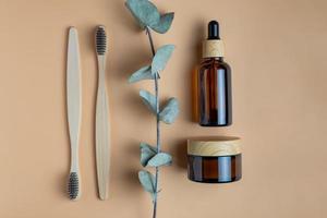 personal hygiene kit. Bath and Skin Care Accessories. Daily natural organic bodycare concept, organic bath products. Bamboo Toochbrushes and face cream and serum in dark glass backage with bamboo lid photo