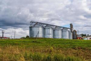 row of agro silos granary elevator with seeds cleaning line on agro-processing manufacturing plant for processing drying cleaning and storage of agricultural products photo