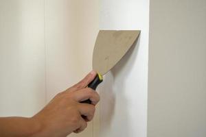 Man repairing crack white wall with spatula photo