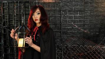 Beautiful woman wearing witch costume holding a lamp in halloween theme photo