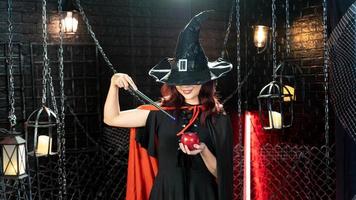 Halloween Girl wearing witch costume with a hat using magic wand with apple for happy in halloween day photo