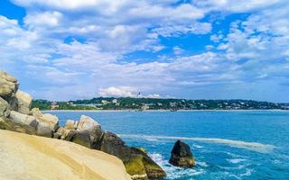 Beautiful surfer waves rocks cliffs at beach Puerto Escondido Mexico. photo