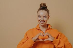 Thankful young female showing love sign with fingers, kind woman expressing gratitude and support photo