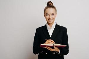 Business woman in dark suit writing in note book photo