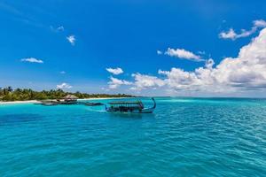 Inspirational Maldives beach design. Maldives traditional boat Dhoni and perfect blue sea with lagoon bay. Luxury tropical resort hotel paradise coast. Paradise shore with white sand, palm trees photo