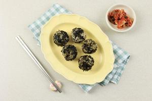 Korean Food Salted Sesame Oil Seaweed and Rice Ball or Jumeokbap, Served with Kimchi. photo