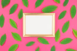 Flat lay with green leaves and frame mockup photo