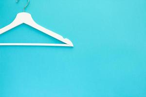 White wooden hangers on blue background photo