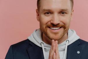 Happy man making praying gesture and smiling at camera photo