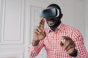 Young african man wearing VR glasses enjoying gaming experience at home photo