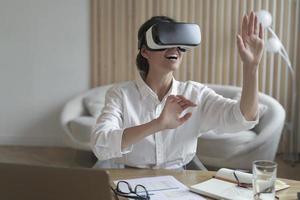 Happy woman office worker wearing vr goggles interacting with virtual reality at work photo
