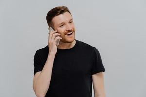 Excited man having pleasant conversation on mobile phone and feeling happy photo