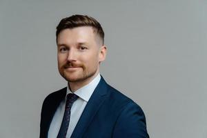 Confident happy executive manager looking at camera and smiling while posing against grey background photo