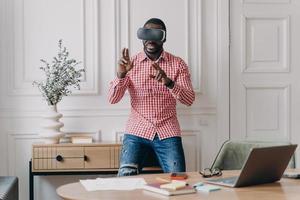Young programmer or software developer African American man in VR headset glasses testing 3D games photo