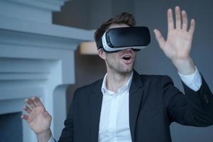 Man entrepreneur in formal suit sitting at home office while testing VR goggles photo