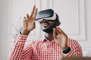 Black man in VR glasses experiencing 3D technology of augmented reality photo