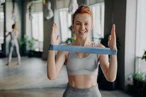Portrait of young sporty redhead woman in sportswear with resistance rubber band photo